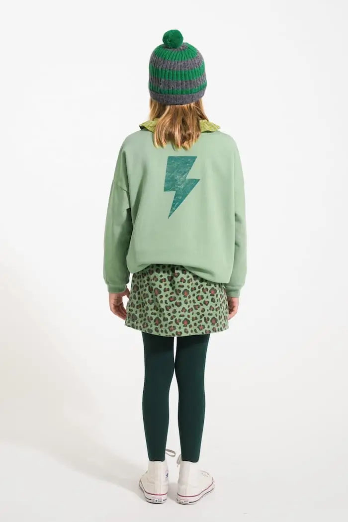 Vista trasera de niña con falda verde de animal print y sudadera verde de Piupiuchick.