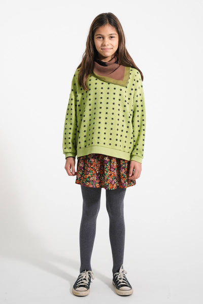 Niña con sudadera verde con estampado de estrellas y falda multicolor de Piupiuchick