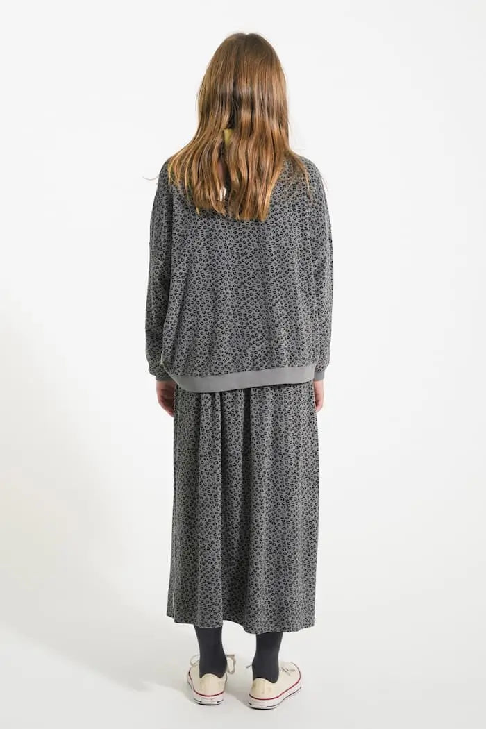Niña con conjunto gris de rizo con estampado de animal print, falda larga y sudadera. Vista atrás, Piupiuchick.