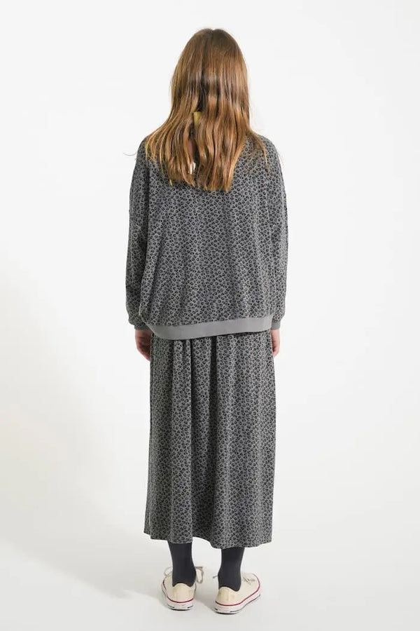 Niña con conjunto gris de rizo con estampado de animal print, falda larga y sudadera. Vista atrás, Piupiuchick.