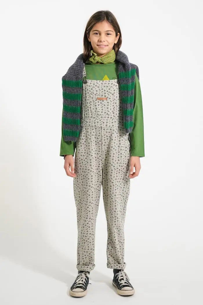 Niña con peto gris clarito con flores negros, camiseta verde y jersey gris con rayas verdes de Piupiuchick.