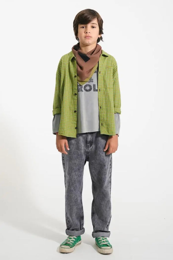 Niño con vaqueros negros, camiseta gris de rizo y camisa verde de cuadros, todo de Piupiuchick.