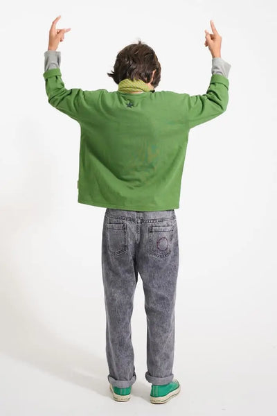 Niño con camiseta verde de manga larga y pantalones negros unisex, vista trasera.