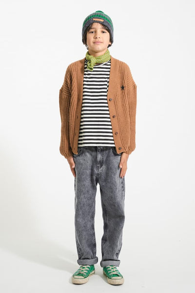 Niño con camiseta Piupiuchick de rayas horizontales negras sobre blanco bajo un cárdigan marrón de punto con botones y pantalón denim negro efecto lavado