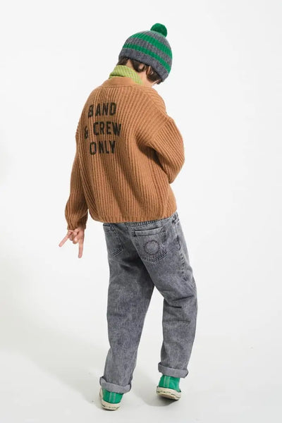 Niño con cárdigan marrón de punto con botones de Piupiuchick y texto estampado “Band & Crew Only”, y con pantalón denim negro lavado con logo bordado en bolsillo trasero izquierdo 