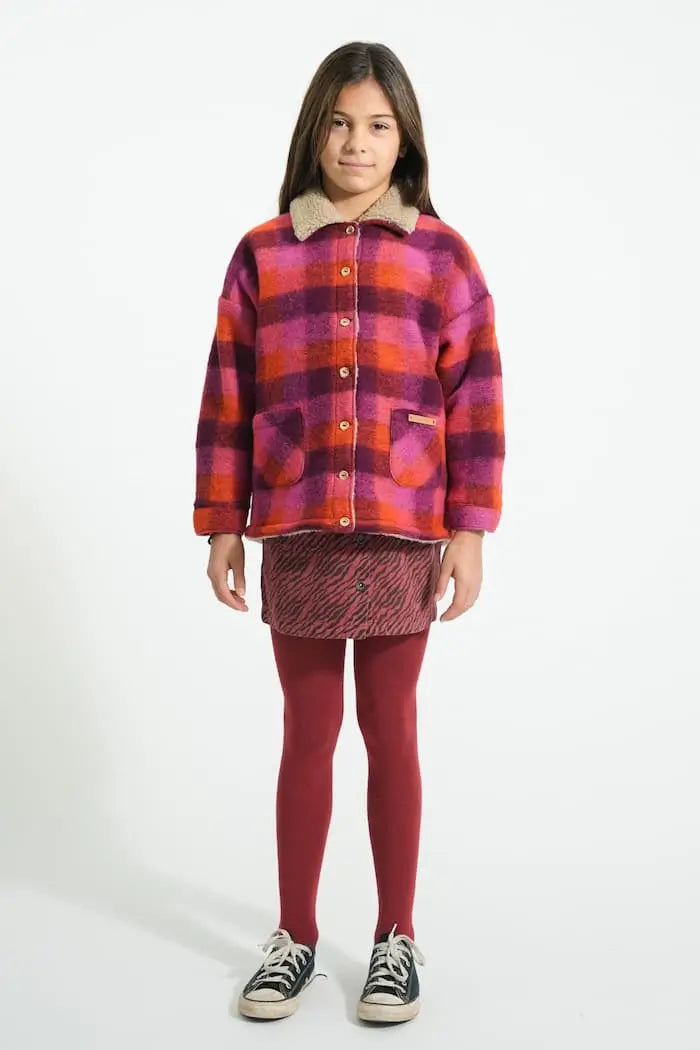 Niña vistiendo falda corta burdeos con estampado de cebra y chaqueta de cuadros multicolor de Piupiuchick.