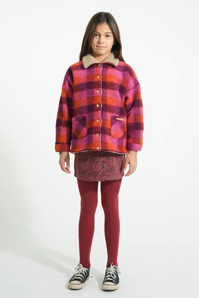 Niña vistiendo falda corta burdeos con estampado de cebra y chaqueta de cuadros multicolor de Piupiuchick.