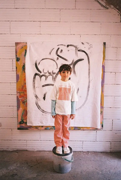 Niño vistiendo pantalones blancos con estampado de caleidoscopios y camiseta de manga corta, ambas prendas de Weekend House Kids.